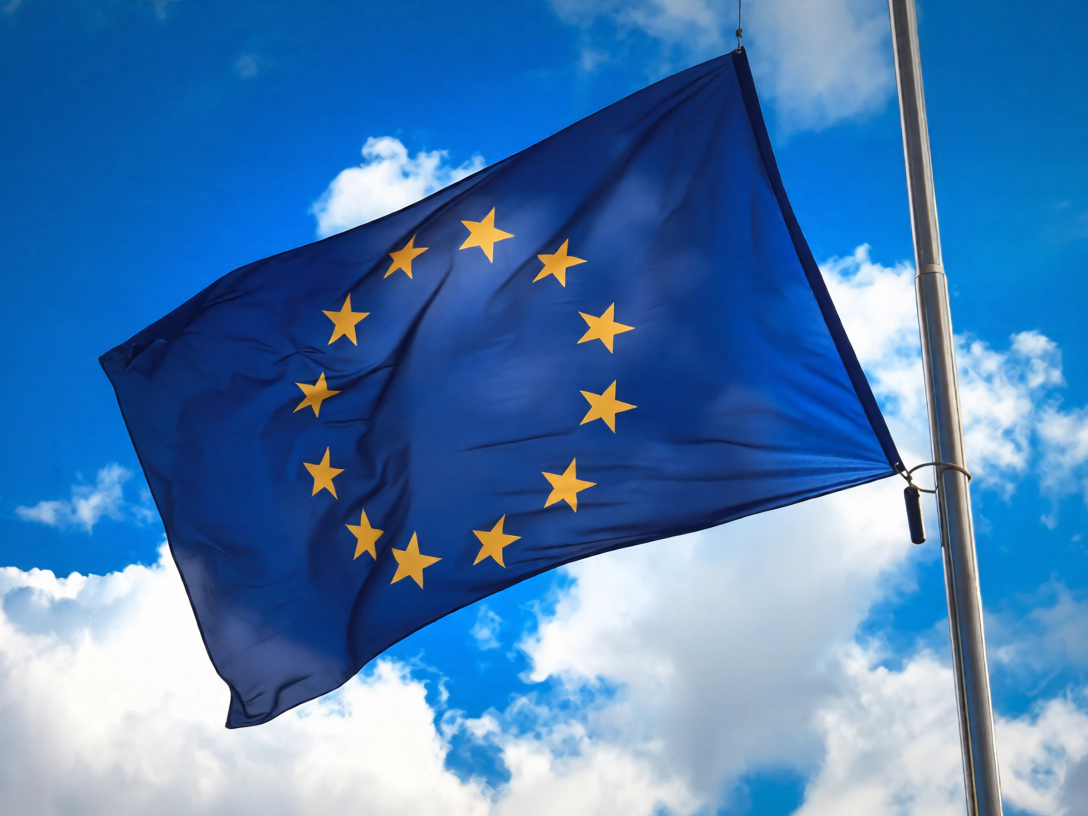 La bandiera dell’Unione europea sventola su un pennone contro il cielo azzurro